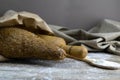 A loaf of bread along with rocking for the dough in a craft bag stand on a wooden table, next to it is satiated with flour. Top