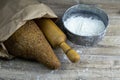 A loaf of bread along with rocking for the dough in a craft bag stand on a wooden table, next to it is satiated with flour. Top