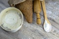 A loaf of bread along with rocking for the dough in a craft bag stand on a wooden table, next to it is satiated with flour. Top