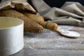 A loaf of bread along with rocking for the dough in a craft bag stand on a wooden table, next to it is satiated with flour. Top