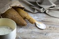 A loaf of bread along with rocking for the dough in a craft bag stand on a wooden table, next to it is satiated with flour. Top