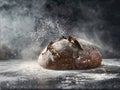 A loaf of bread is being sprinkled with flour