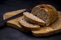 Loaf of bread with knife on wooden board. Dark background Royalty Free Stock Photo