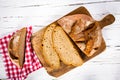 Loaf of bread, partly sliced, on wooden board.