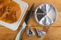 Bread with raisin on cutting board, knife, creamy cheese in foil in round box, slice of cheese on table. Top view