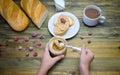 A loaf of bread and a sandwich a piece of loaf with nut paste a Cup and children`s hands holding a jar with nut paste and berry