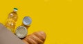 A loaf of bread, sunflower oil and canned food in a paper bag on a yellow isolated background. Food delivery, donation, banner.