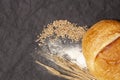 Loaf of bread with wheat ears and flour on a black background, top view Royalty Free Stock Photo