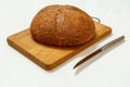 Loaf of bread on wooden cutting board with kitchen knife Royalty Free Stock Photo