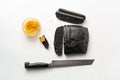 Loaf of charcoal brea partly sliced, pike caviar, bread knife on white background Royalty Free Stock Photo