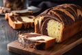 a loaf of chocolate marbled bread on a cutting board with a slice cut out of it and a knife next to it on a black surface Royalty Free Stock Photo