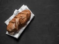 Loaf dark buckwheat bread on white textile napkin black table background. Fresh delicious homemade healthy bake. Bakery Royalty Free Stock Photo