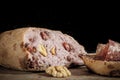 Loaf of French sourdough, called also Pain de campagne, stuffed with meat and walnuts on a black background with a slice of bread Royalty Free Stock Photo