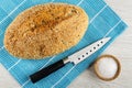 Loaf of bread with sesame, knife on napkin, salt in bowl on wooden table. Top view Royalty Free Stock Photo