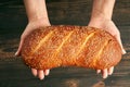 Loaf of fresh made white bread in woman hands on wooden table background Royalty Free Stock Photo