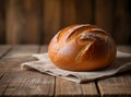 Loaf of fresh rustic bread on a wooden table against a blurred background Royalty Free Stock Photo