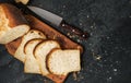 Loaf of fresh sliced white bread laid out on a cutting board and a sharp knife nearby. Top view with copy space bread crumbs on