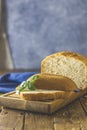 Loaf of freshly baked bread with basil and bread slices on wooden board over rustic wooden table background. Shallow depth of Royalty Free Stock Photo