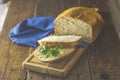 Loaf of freshly baked bread with basil and bread slices on wooden board over rustic wooden table background. Shallow depth of Royalty Free Stock Photo