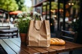 Loaf of freshly baked wheat bread and a craft paper bag lie on the table of a street cafe, bakery and confectionery Royalty Free Stock Photo