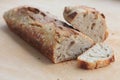 A loaf of homemade bread with two slices on wooden board.