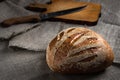 Loaf of homemade rye fresh bread with knife and cutting board lying on an old wooden table and sackcloth. rural food background in Royalty Free Stock Photo