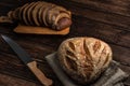 Loaf of homemade rye fresh bread and one sliced loaf with knife and cutting board lying on an old wooden table. rural food Royalty Free Stock Photo