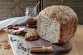 loaf of homemade whole grain bread and a cut slice of bread on a wooden cutting board. A mixture of seeds and whole Royalty Free Stock Photo