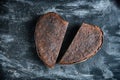 Loaf rye whole grain yeast-free sourdough bread in shape of heart cut in half, on black table with spices, white flour Royalty Free Stock Photo