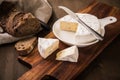 Loaf of soft blue cheese from cow milk on porcelain plate with walnut bread, knife, linen towel and dark brown wooden board as Royalty Free Stock Photo