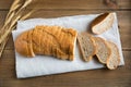A loaf of wheat bread with bran is cut into slices and lies on a linen napkin. Royalty Free Stock Photo