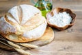 Loaf of white rustic bread on the wooden kitchen cutting board, white flour in the wood bowl and olive oil bottle Royalty Free Stock Photo