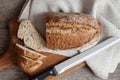 Loaf of whole wheat bread with slices on wooden board on kitchen table Royalty Free Stock Photo