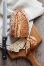 Loaf of whole wheat bread with slices on wooden board on kitchen table Royalty Free Stock Photo