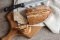 Loaf of whole wheat bread with slices on wooden board on kitchen table Royalty Free Stock Photo