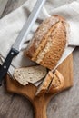 Loaf of whole wheat bread with slices on wooden board on kitchen table Royalty Free Stock Photo