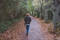 Loan, adult woman seen walking along a slippery footpath at the edge of a forest.