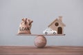 Loan bags, wood home with car in a house on balance scale. Concept family financial management, mortgage and payday loan or cash