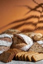 Loaves of bread of various shapes, spikelets of oats and buckwheat grains on a orange background