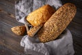 Loaves and slices of fresh grain bread in a basket with a towel on a dark wooden background Royalty Free Stock Photo