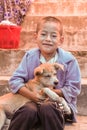 Lobesa Village, Punakha, Bhutan - September 11, 2016: Little Bhutanese boy sitting on stairs hugging a stray dog in the street.