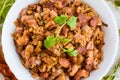 Lobio - the national Georgian dish of beans in a white plate and the ingredients for its preparation on a wooden table