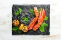Lobster claw with black pasta and vegetables on the black stone plate. Seafood. Top view. Royalty Free Stock Photo