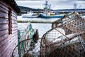 Lobster traps and crab traps stacked on a dock with fishing trawlers at background at Whiteway Newfoundland Royalty Free Stock Photo