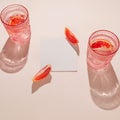 Lobules of bloody orange with white paper card note and two glasse with water on beige pastel background. Summer refreshment