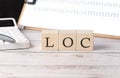 LOC word on a wooden block with clipboard and calcuator Royalty Free Stock Photo