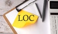 LOC word on a yellow sticky with calculator, pen and clipboard Royalty Free Stock Photo