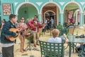 Local artists entertain tourists with their musical instruments on the patio of a restaurant