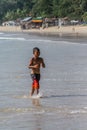Local Asian children on the beach. Three boys playing in the waves. Royalty Free Stock Photo