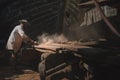 Local Asian worker grinding old wood in shipyard for maintenance.